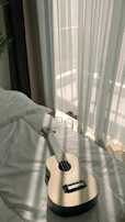 Evening scene of a guitar resting against a chair by a window
