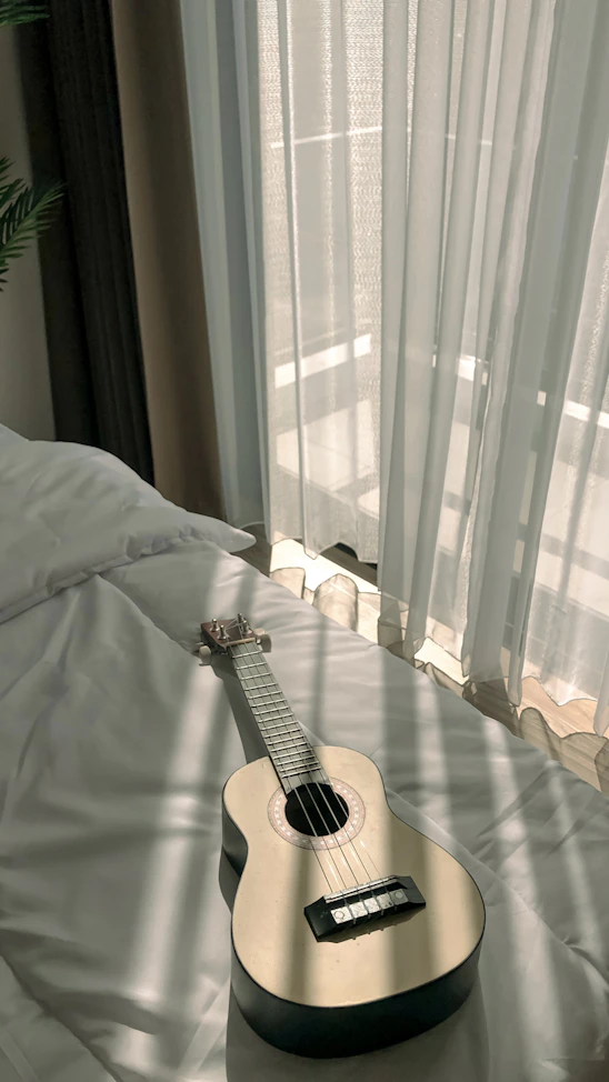 A candid photo of Kentenfromlucca playing guitar in a sunlit studio filled with vintage instruments.