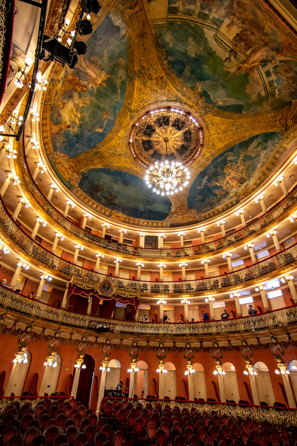 a large ornate ceiling with a chandelier and a large group of people in the front