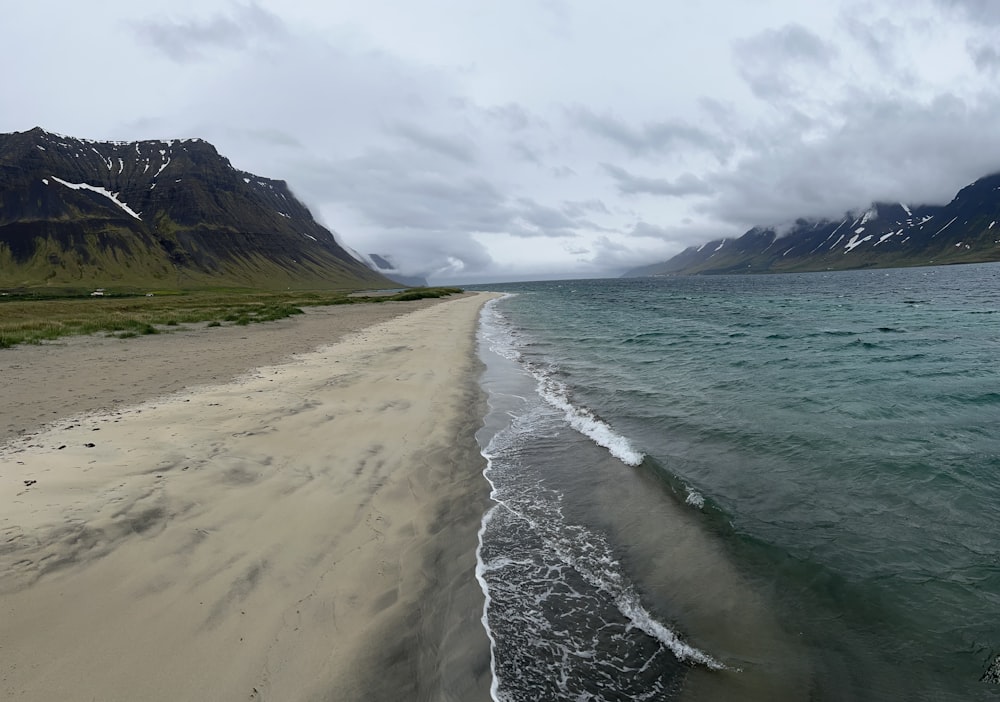 a beach with a body of water and mountains in the background