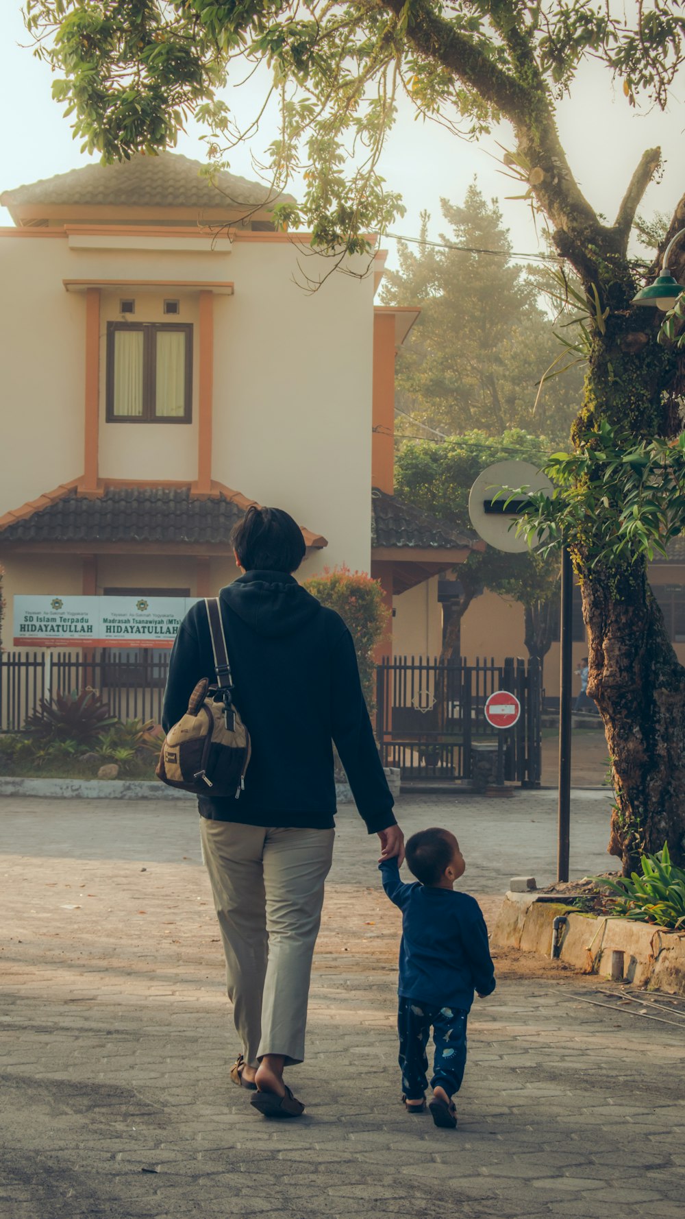 a person and a child walking down a sidewalk