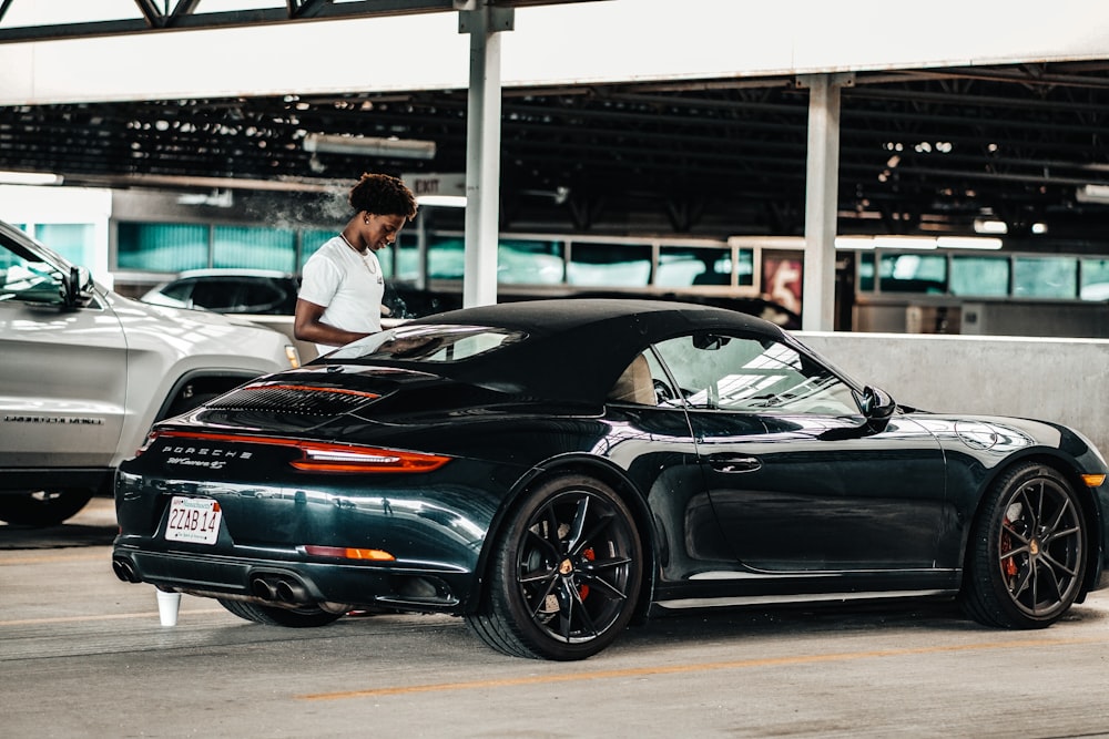 a person standing next to a black car