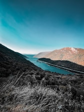 A serene natural landscape showing a clear river flowing through green hills.