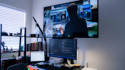 a person sitting at a desk with a computer and a microphone