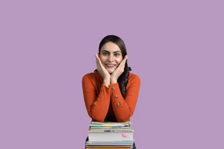 A friendly photo of Swarnima Soni smiling with science books and a laptop nearby.