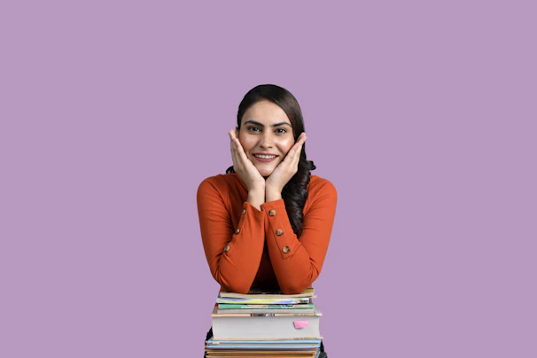 Confident student smiling with books and a modern purple-green gradient background.