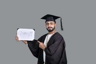 a person wearing a graduation cap and gown holding a sign