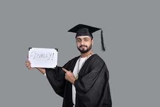a person wearing a graduation cap and gown holding a sign
