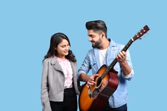 A student and teacher smiling together while practicing guitar chords.