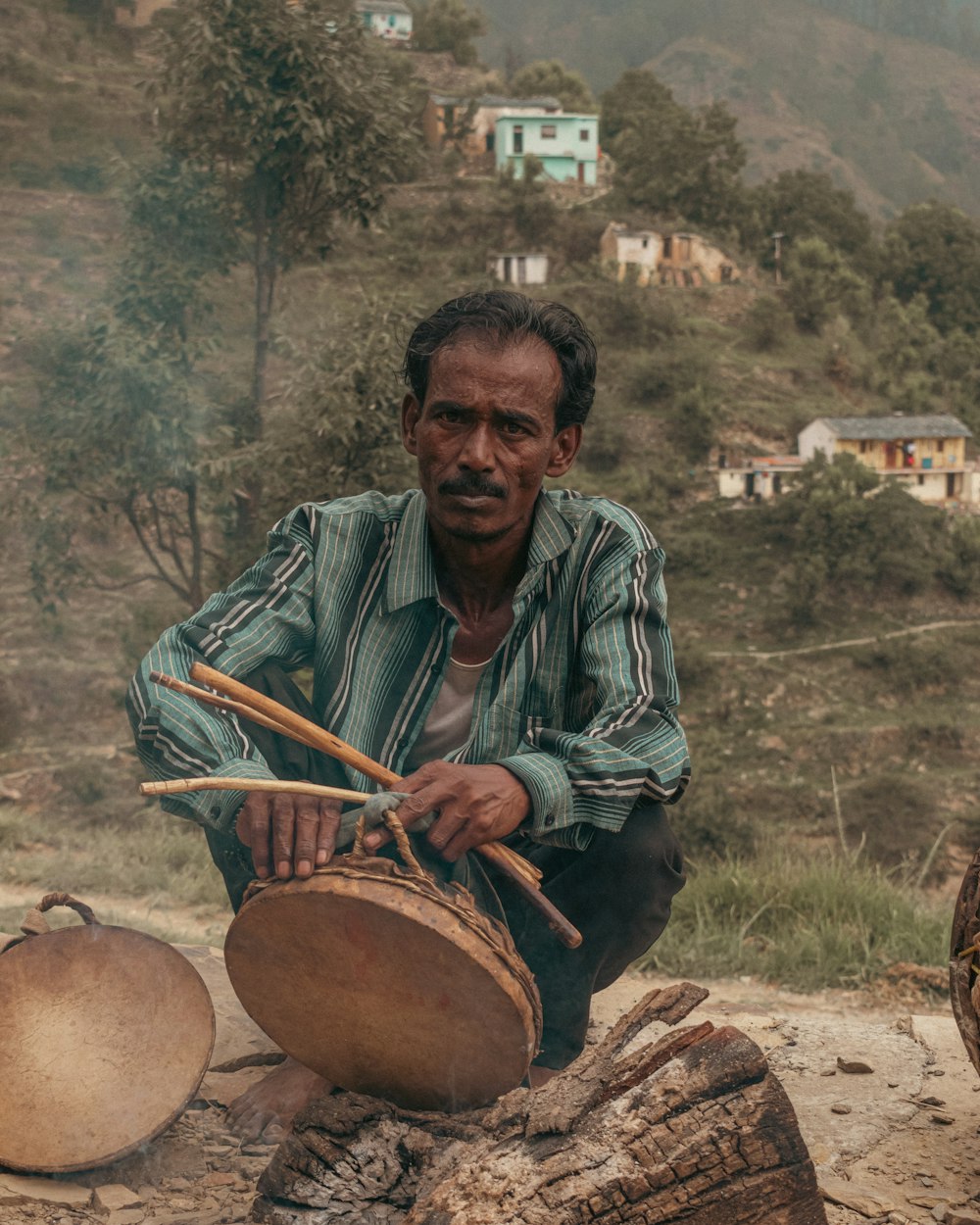 a man sitting outside with a bucket of water and a tree