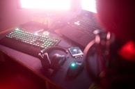 An array of neon-lit gaming keyboards and headphones arranged on a sleek black desk.