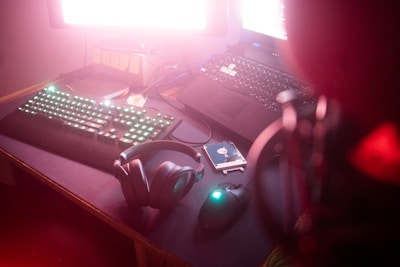 Dark-themed gaming setup with a notebook, headset, and ambient LED lights.