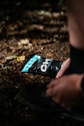 Close-up of a runner lacing up vibrant trail shoes on a rocky path.