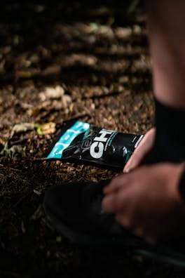 An athlete tying running shoes before a morning jog on a forest trail.