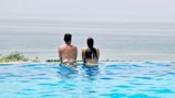 Couple enjoying a quiet moment by the infinity pool with gentle waves in the background