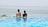 A couple relaxing by the infinity pool with the Adriatic Sea in the background.