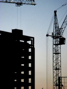 A tower crane towering over a building under construction during sunset.