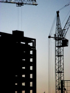 Sunset silhouette of a crane and construction workers finishing up a high-rise project.