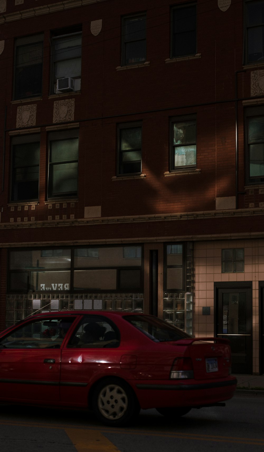 um carro vermelho estacionado em frente a um edifício