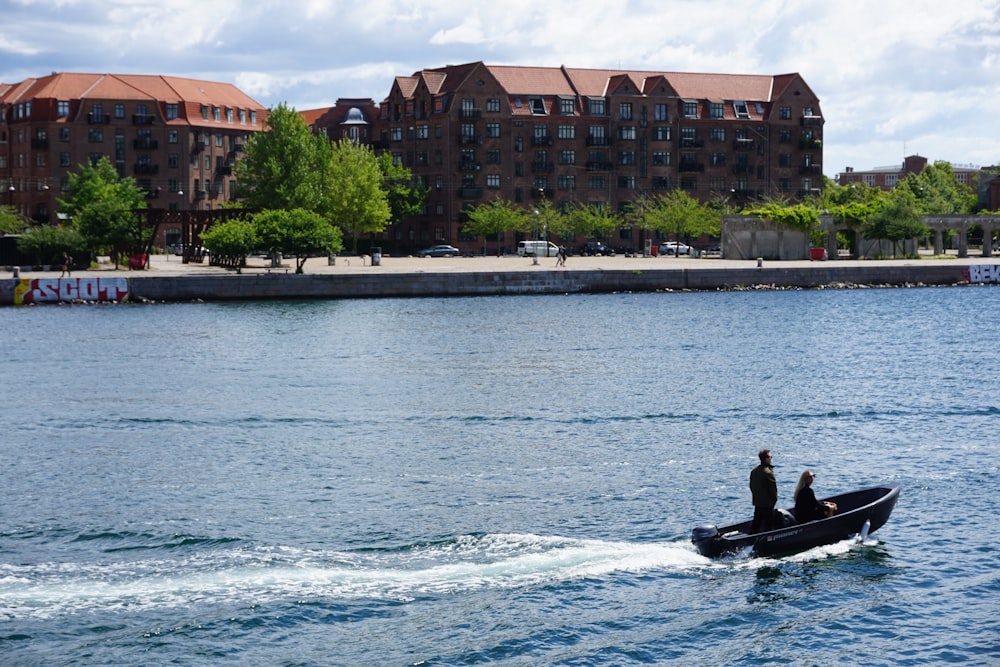 a couple people in a boat in the water by a building