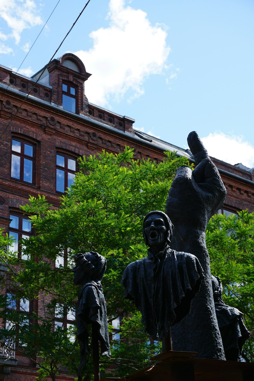 a statue of a man and a woman holding hands in front of a brick building