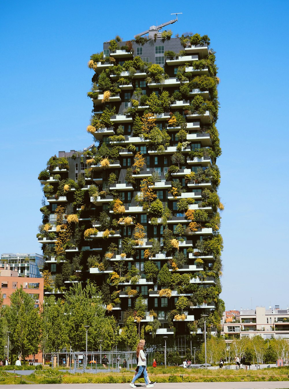 a tall building with many windows with Bosco Verticale in the background