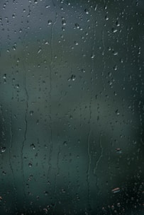 Water droplets cover a transparent surface, likely glass, with a slightly blurred background.