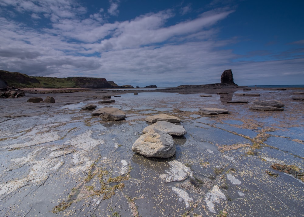 a rocky beach with a body of water in the background