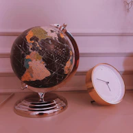 A polished black and gold globe displayed on a minimalist pedestal in a luxury office.
