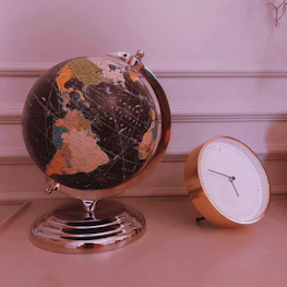 A classic globe and passport on a polished wooden desk.