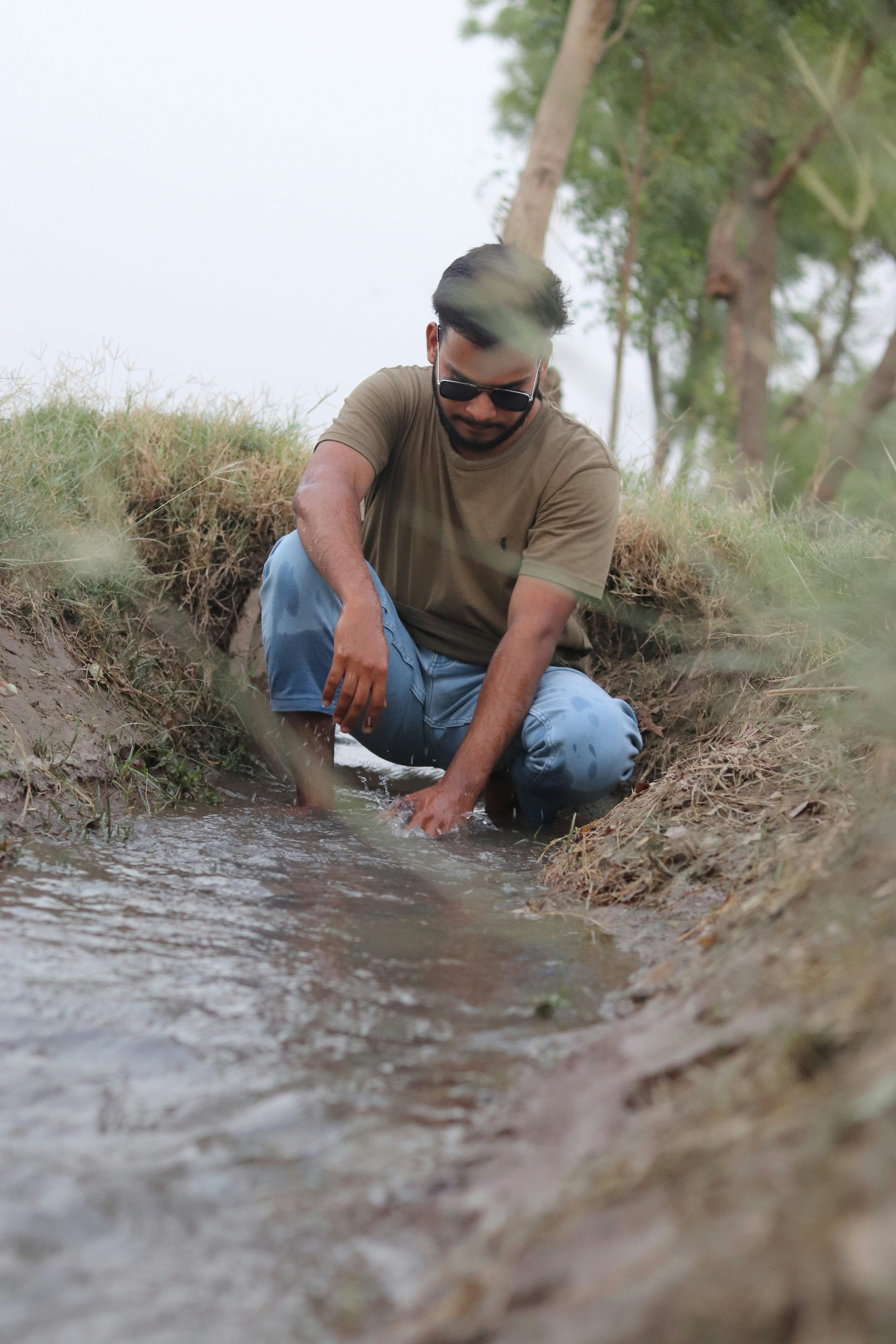 a man squatting in a muddy area