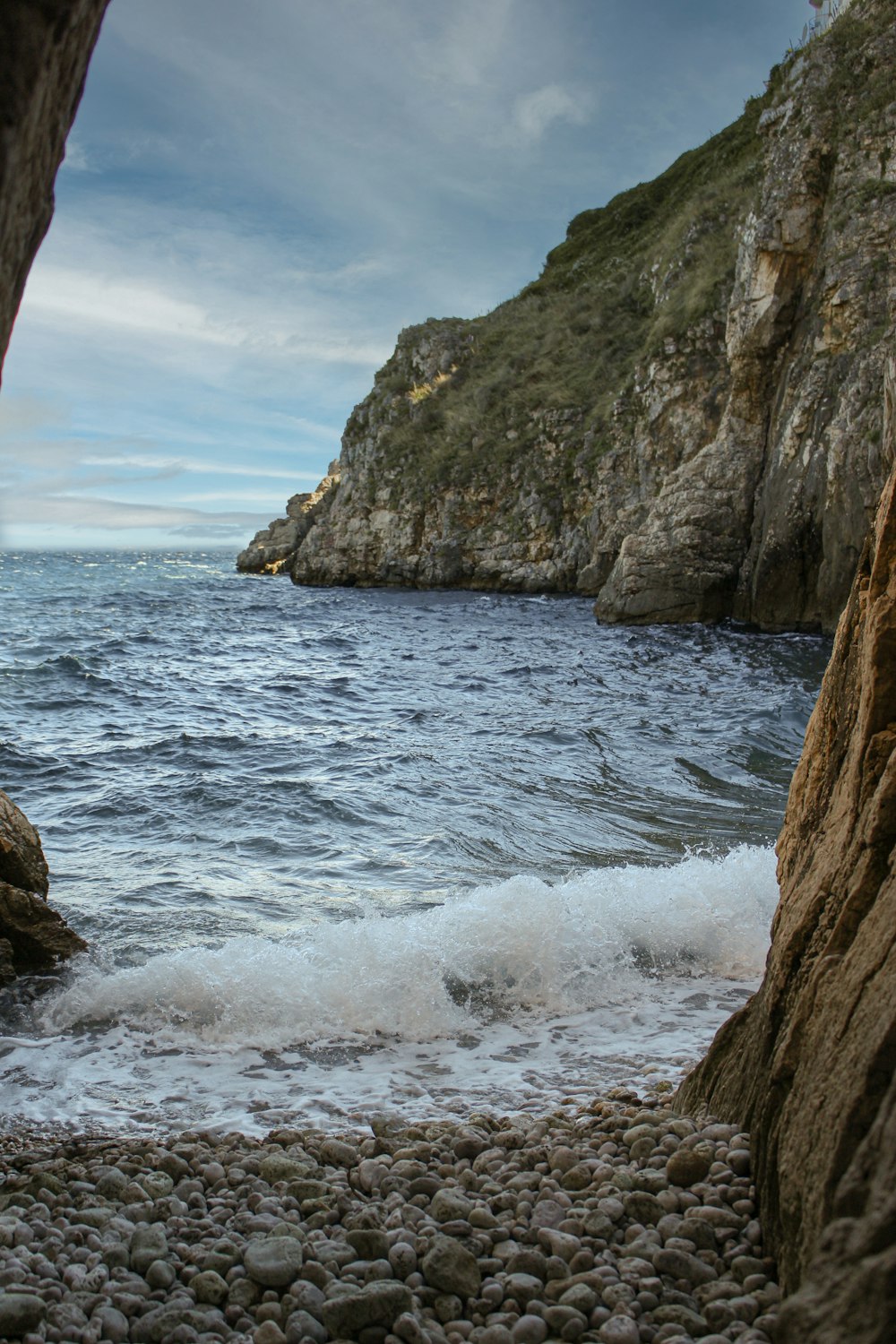 a rocky beach with a large rock formation in the background