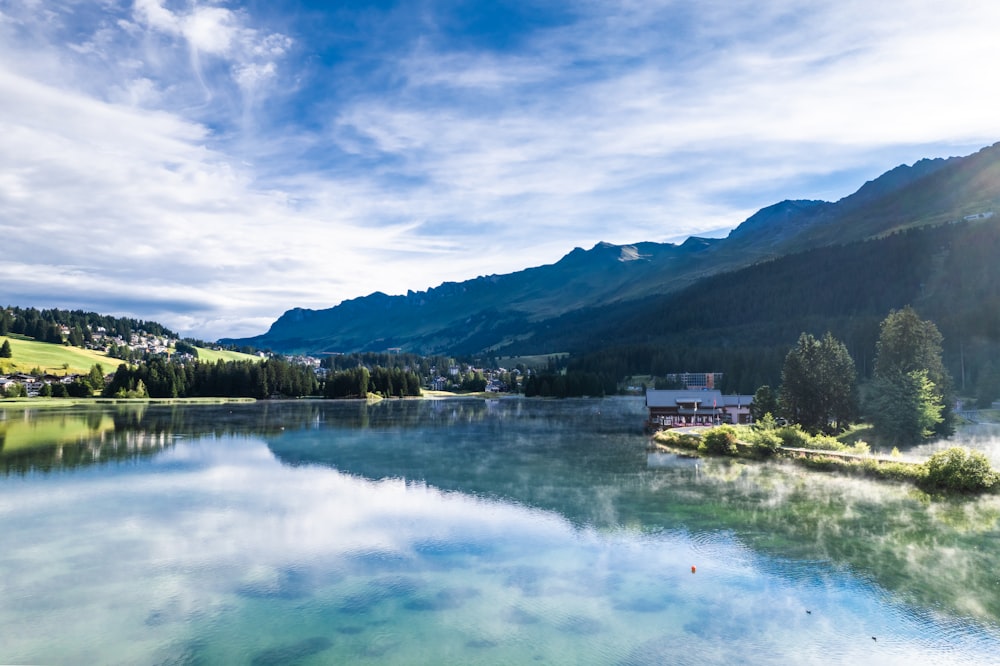 a lake with a house and mountains in the background