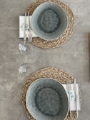 Soft, neutral-toned placemats and napkins laid out on a rustic kitchen table.