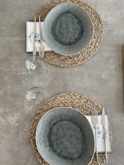 Woven jute table mat set laid out neatly on the dining table with simple ceramic dishes.