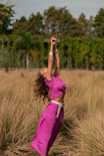 A vibrant photo of a woman wearing a stylish pink fitness outfit, smiling while stretching outdoors.