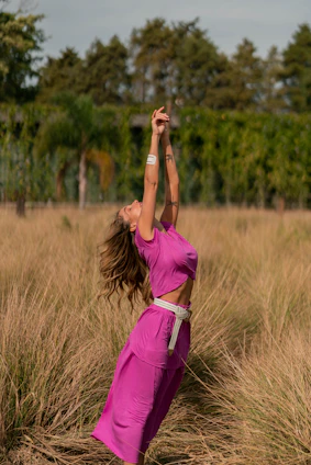 A smiling woman stretching outdoors in the morning sunlight, embodying vitality and wellness.
