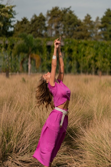 A joyful woman stretching outdoors in the morning sun, symbolizing health and energy.