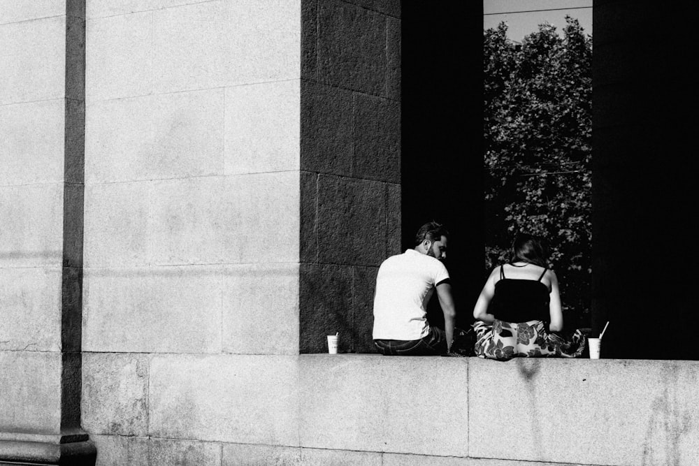 a couple of people sitting on a ledge