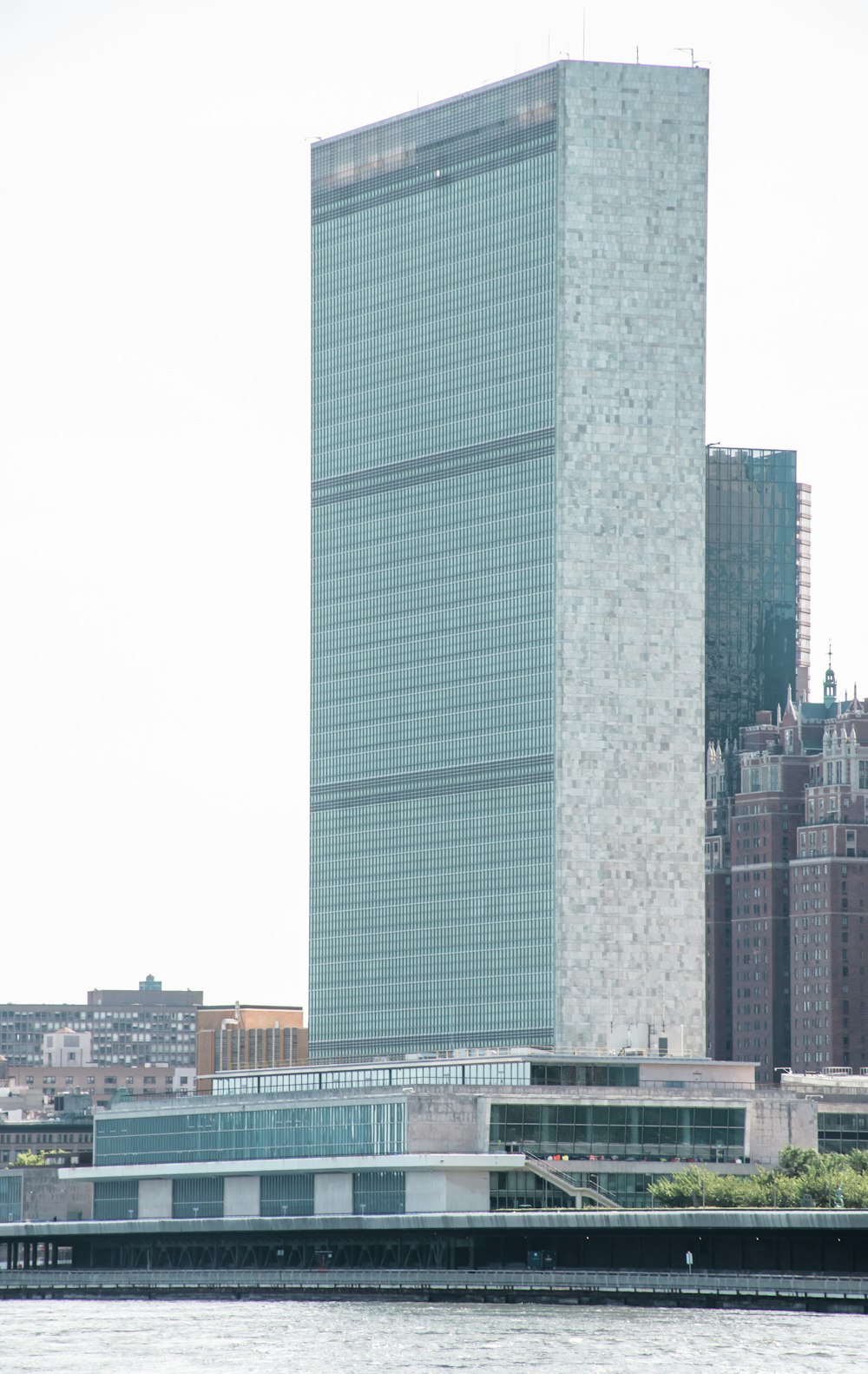 un grand bâtiment au bord de l’eau avec le Siège des Nations Unies en arrière-plan