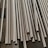 Multiple metallic tubes arranged in parallel lines, reflecting light and exhibiting a shiny surface. They are uniformly cylindrical and appear to be made of stainless steel.