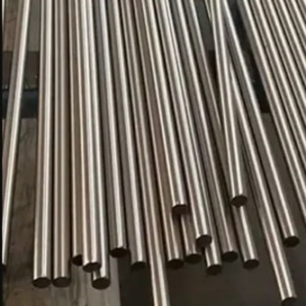 Multiple metallic tubes arranged in parallel lines, reflecting light and exhibiting a shiny surface. They are uniformly cylindrical and appear to be made of stainless steel.