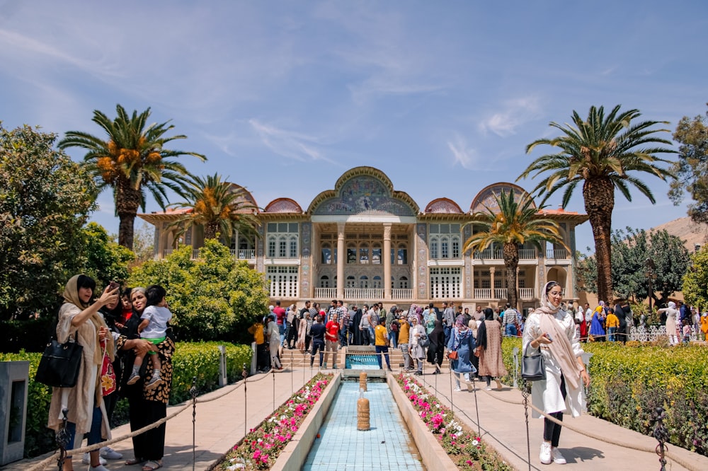 a group of people walking on a walkway in front of Eram Garden