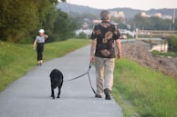a man and a woman walking a dog on a path