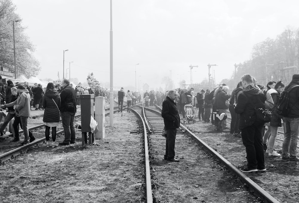 a group of people standing on train tracks