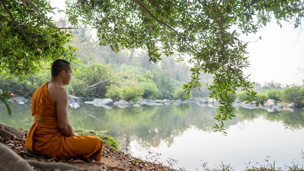 a person sitting on a rock by a lake