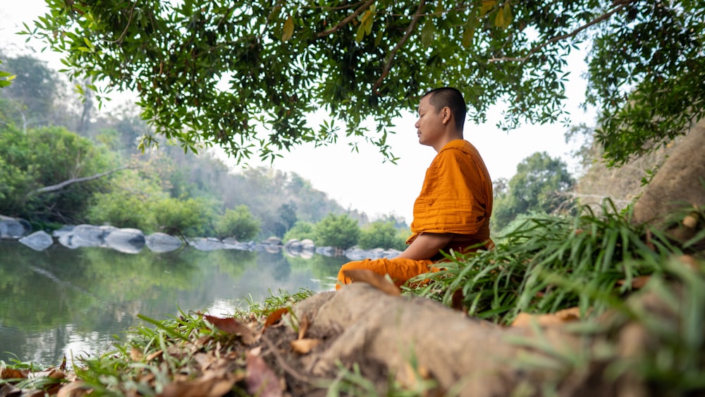 a man sitting on a rock by a river