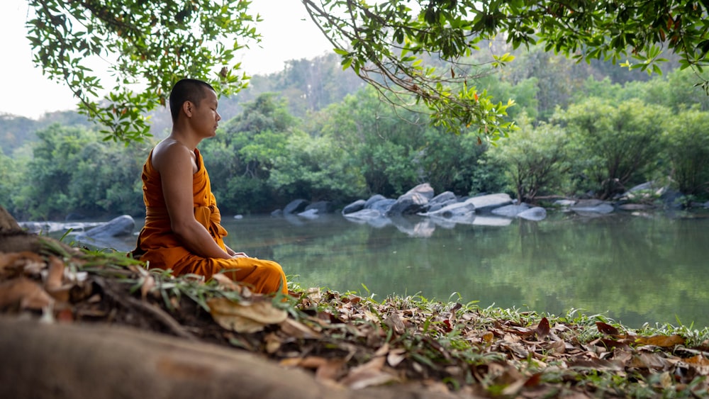 a person sitting on a rock by a river