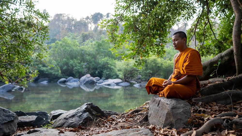 a man sitting on a rock by a river