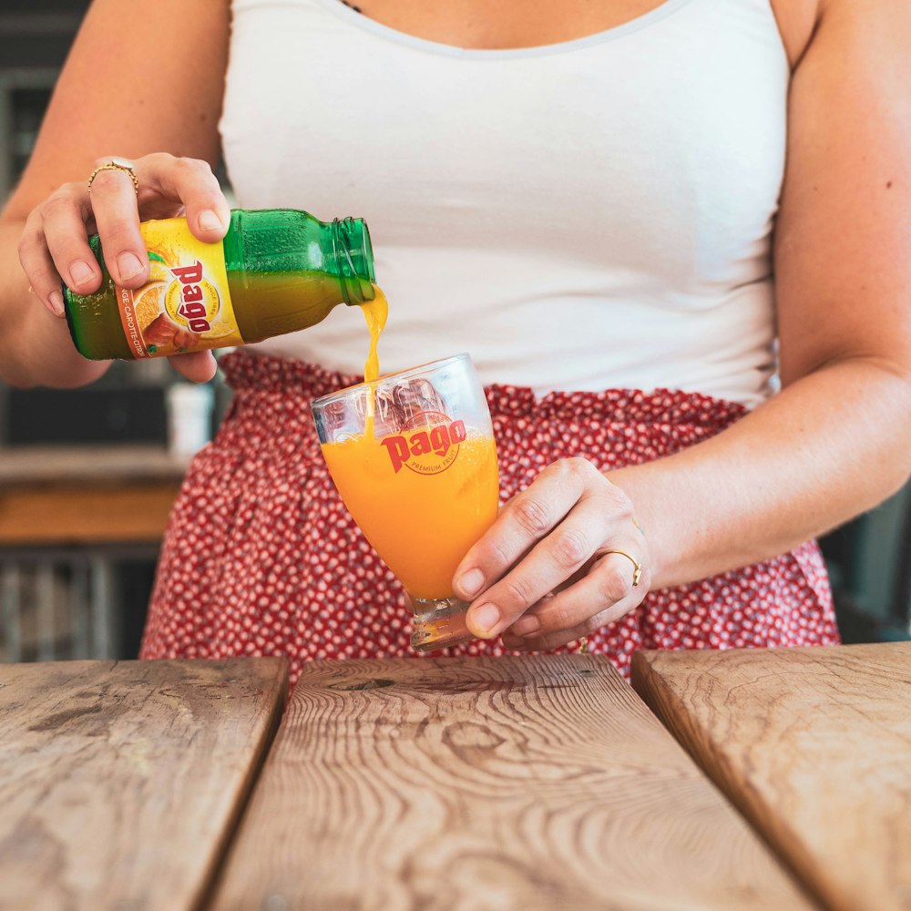 a woman holding a drink and a glass of orange juice